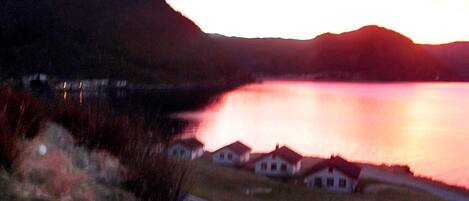 A view of a lake with houses in the foreground and a mountain in the background.