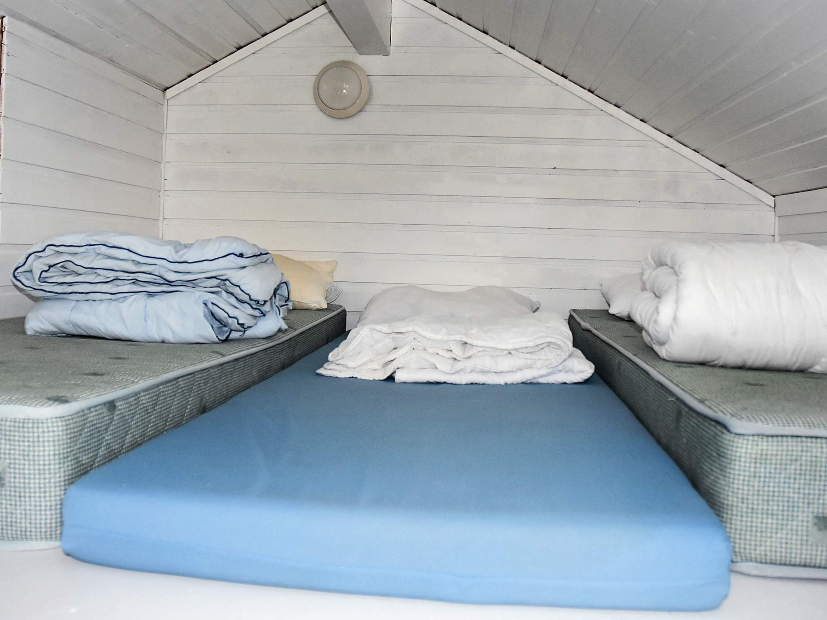 Un petit espace de couchage fermé, comprenant deux matelas et un matelas bleu placé au centre.
