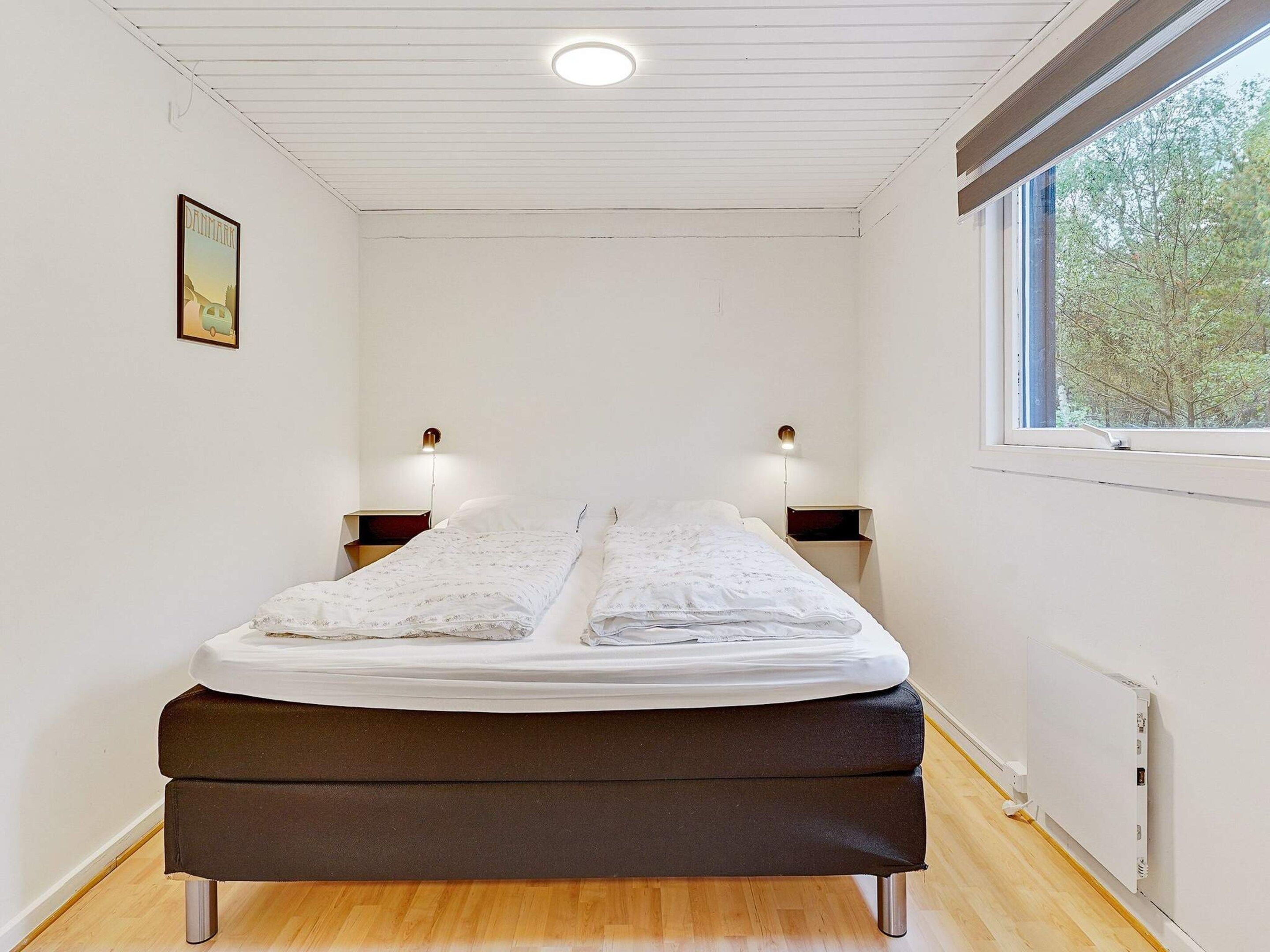 Une chambre à coucher avec un lit, des lampes de chevet, une fenêtre et un radiateur.