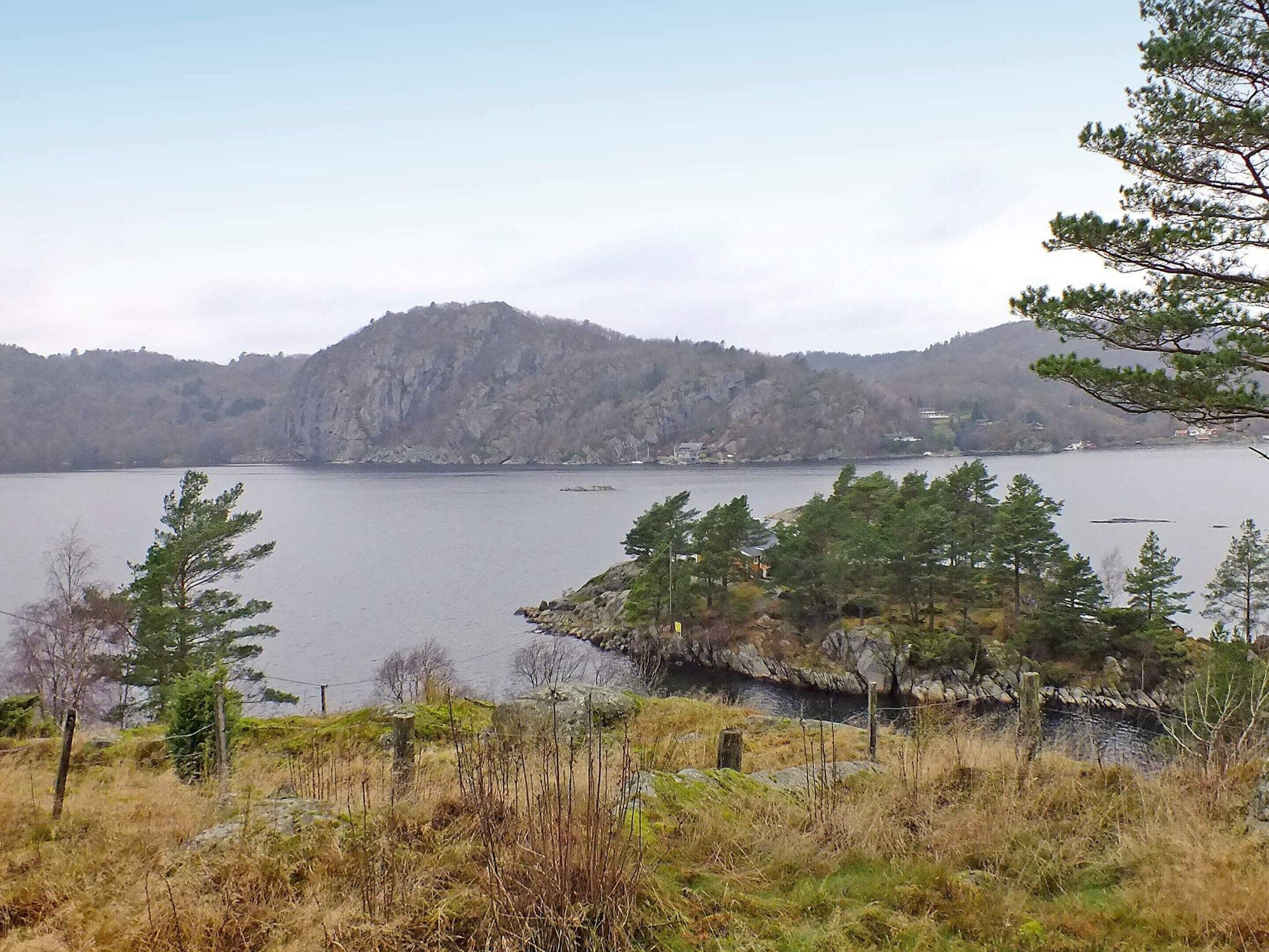 Un lago con un litorale roccioso, circondato da colline e vegetazione rada.