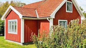 Ein rotes Holzhaus mit geneigtem Dach und zwei Fenstern.