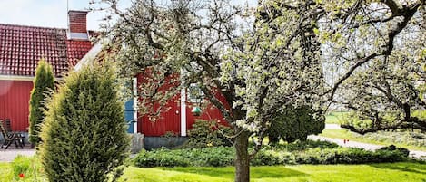 Un bâtiment rouge avec un toit en tuiles, entouré d’herbe verte et d’arbres.