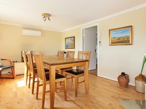 A dining area with a wooden table and chairs, a white door, and two framed pictures on the wall. - Holiday Home in Söderåkra (Soderakra)
