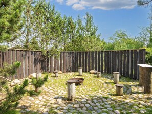 Un jardí amb un camí de pedra, pals de fusta i una tanca de fusta.