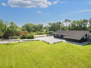 Il s’agit d’une propriété résidentielle dotée d’une allée pavée, d’une structure en bois et d’un bâtiment noir avec un toit recouvert de tuiles.