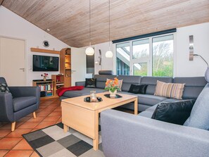 Una sala de estar moderna con un sofá, sillones, una mesa de centro y un televisor.