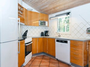 A compact kitchen with wooden cabinets, a microwave, a coffee maker, and a dishwasher. - 8 Person Holiday Home in Ringkobing (Ringkobing)
