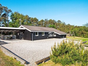 A black building with a gravel driveway and a covered outdoor seating area. - 8 Person Holiday Home in Ringkobing (Ringkobing)