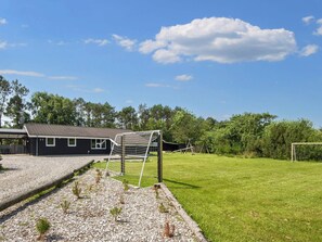 Ein Wohnhaus mit Garten, überdachter Terrasse und umzäuntem Grundstück sowie einem Fußballtor.