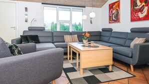 Un salon moderne avec des canapés gris, une table basse en bois et un tapis à carreaux.