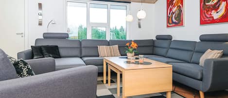 A modern living room with grey sofas, a wooden coffee table, and a checkered rug.