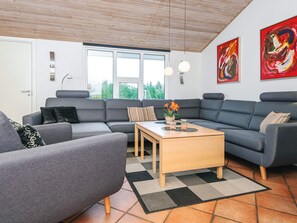 Ein modernes Wohnzimmer mit grauen Sofas, einem Holztisch und einem Schachbrettmuster-Teppich.