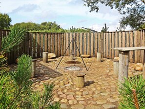 An outdoor patio area with a stone floor, wooden posts, and a swing set. - 8 Person Holiday Home in Ringkobing (Ringkobing)