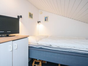 Ein Schlafzimmer mit einem Bett, einem Fernseher auf einem Holzständer und zwei Wandleuchten.