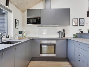 A modern kitchen with grey cabinets, a stainless steel oven, and a microwave. - 5 Star Holiday Home in Bogense (Bogense)
