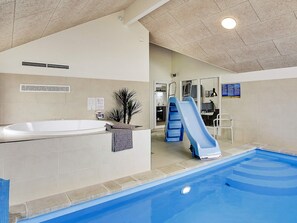 Ein Innenpool mit Rutsche, Whirlpool und Duschbereich.
