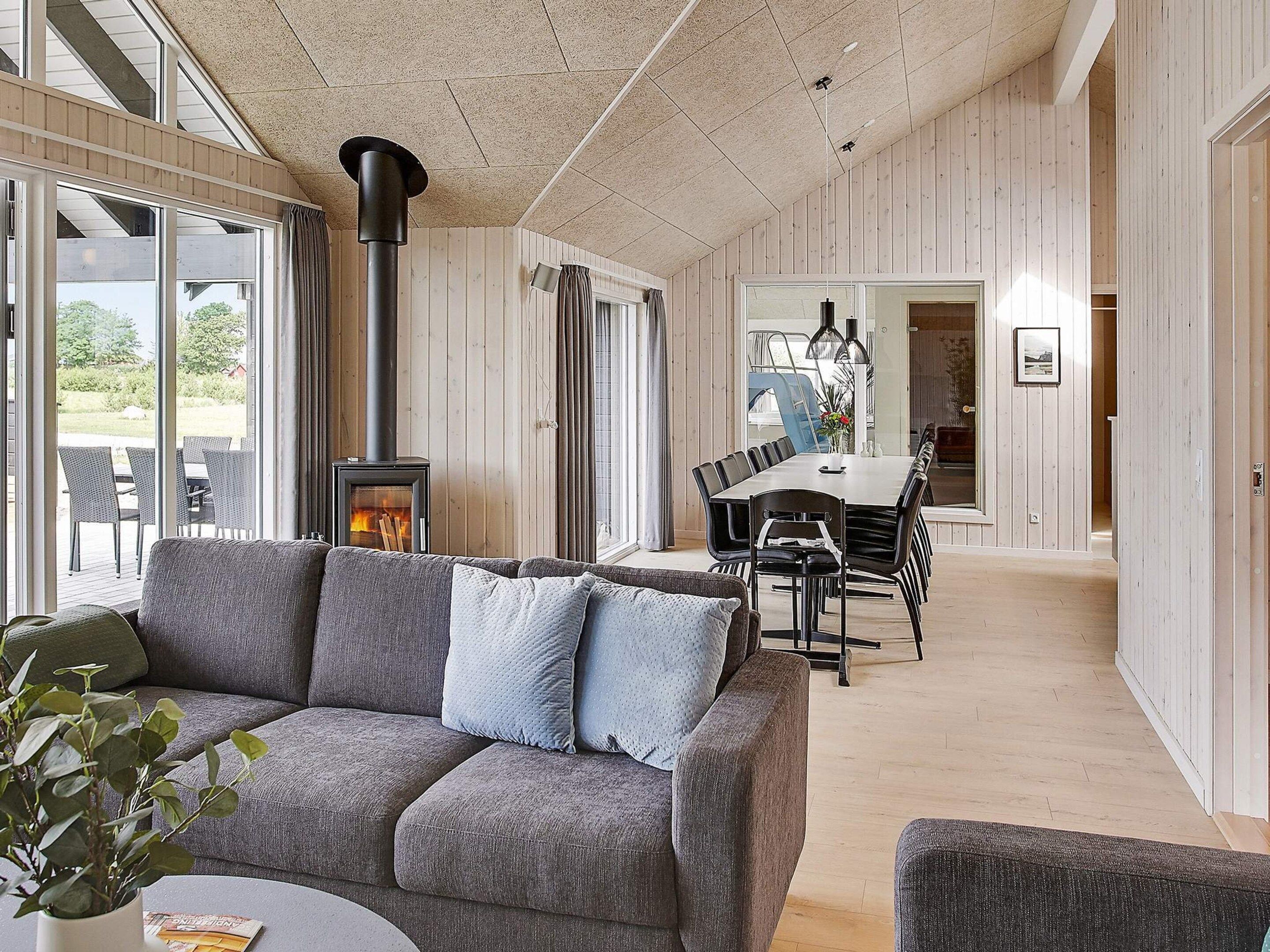 A modern interior with a sofa, dining table, and a wood-burning stove.