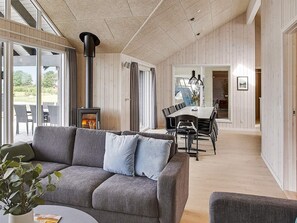 A modern interior with a sofa, dining table, and a wood-burning stove.