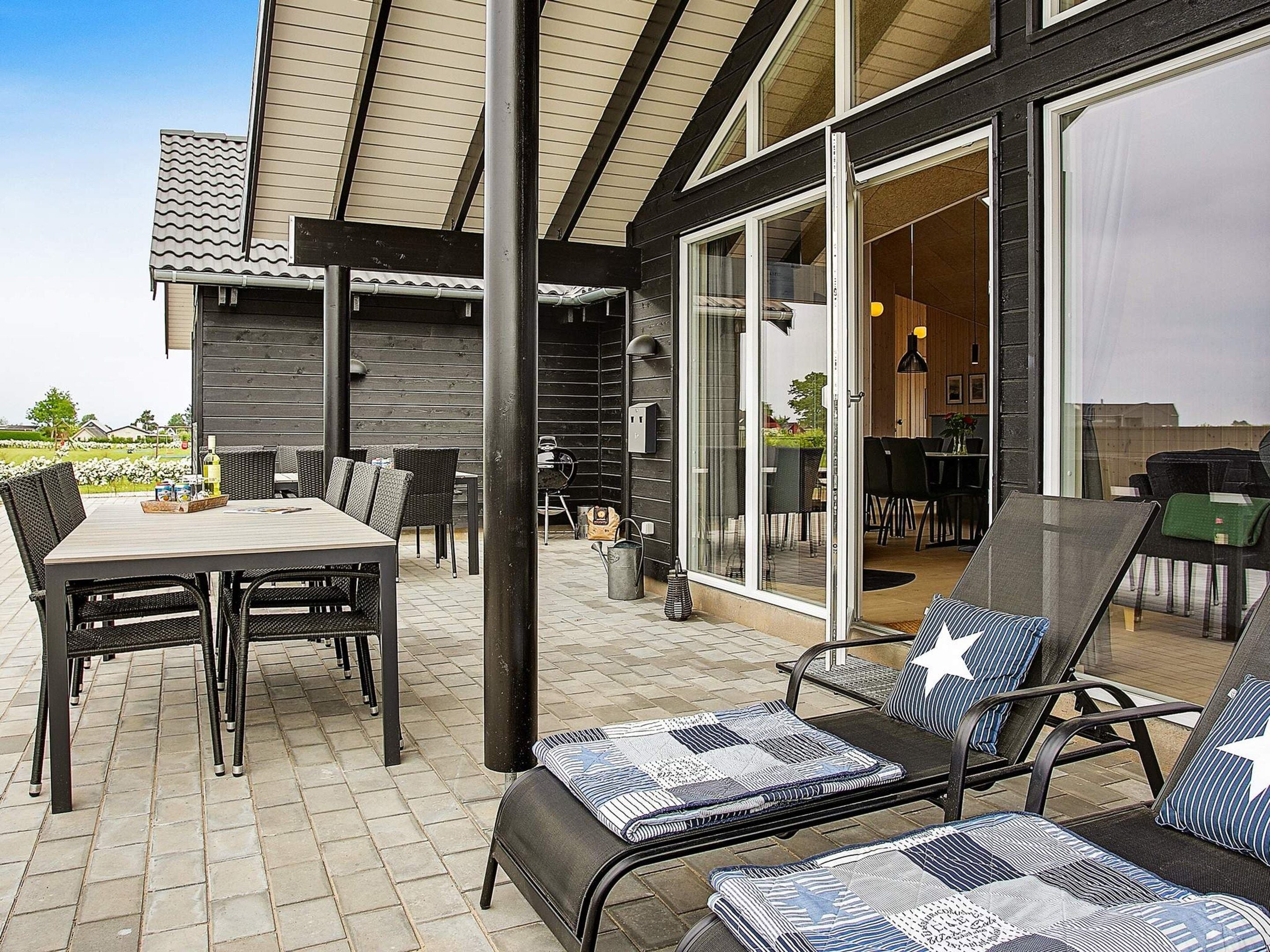 An outdoor patio with a table and chairs, a grill, and a covered seating area.