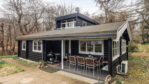 A cabin with a covered patio, a grill, and a small outdoor seating area. - 6 Person Holiday Home in Dronningmolle-by Traum (Dronningmolle)