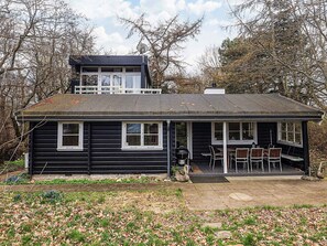 A two-story log cabin with a balcony, a patio with outdoor seating, and a satellite dish. - 6 Person Holiday Home in Dronningmolle-by Traum (Dronningmolle)