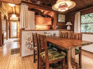A wooden interior with a dining table, chairs, a kitchen area, and a window with a view of greenery. - 6 Person Holiday Home in Dronningmolle-by Traum (Dronningmolle)