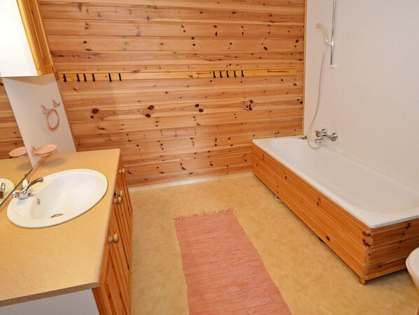 A wooden-paneled bathroom with a sink, a bathtub, and a shower. - 10 Person Holiday Home in Tvedestrand (Arendal)