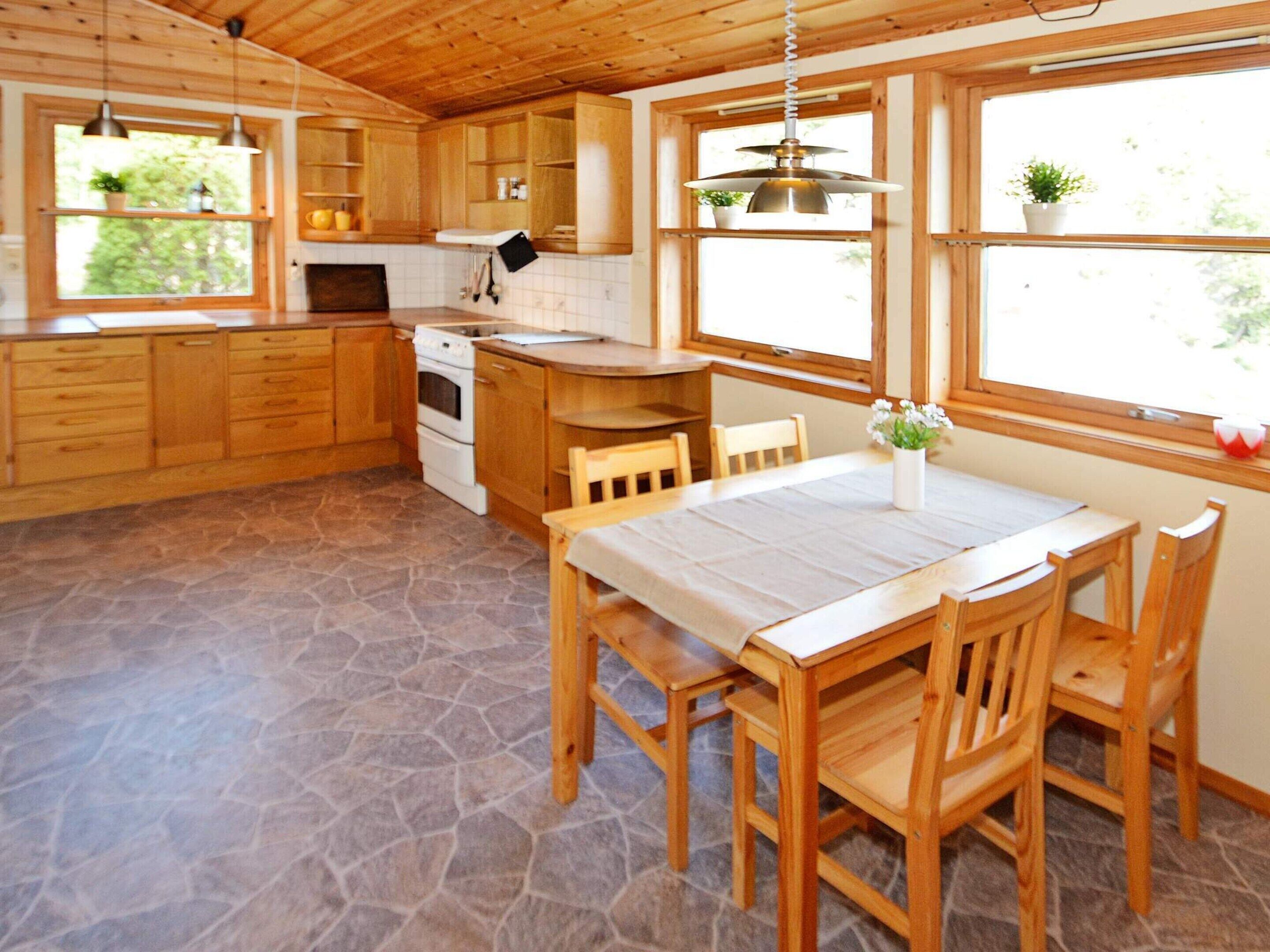 A kitchen with wooden cabinets, a stove, and a dining table with chairs.