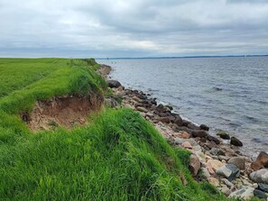 A coastal landscape with a grassy embankment and a rocky shoreline. - 5 Star Holiday Home in Sydals (Sydals)