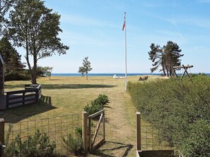 A grassy area with a flagpole, a wooden fence, and a view of the sea. - 5 Star Holiday Home in Sydals (Sydals)