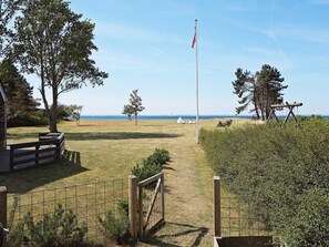 A grassy area with a flagpole, trees, and a view of the sea. - 5 Star Holiday Home in Sydals (Sydals)