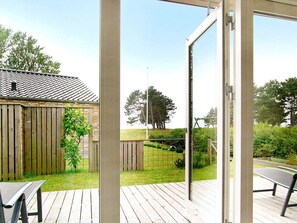 A wooden deck with a view of a fenced backyard and a building with a tiled roof. - 5 Star Holiday Home in Sydals (Sydals)