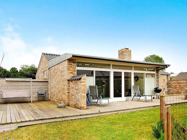 Une maison en briques avec un patio, une cheminée et un espace extérieur aménagé avec des sièges.