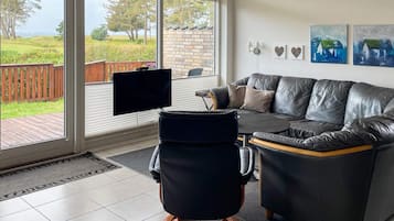 A modern living room with a leather sofa, a black chair, and a TV on a stand.