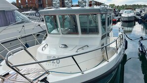 A white boat docked in a marina with a metal railing and a blue rope tied to the bow. - 6 Person Holiday Home in Dyrvik (Frøya)
