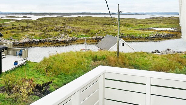 A coastal view with a white building, a dock, and a grassy landscape. - 6 Person Holiday Home in Dyrvik (Frøya)