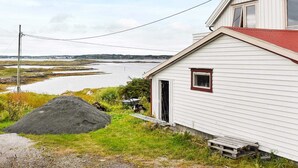 A white building with a red roof, a small porch, and a view of a body of water and distant land. - 6 Person Holiday Home in Dyrvik (Frøya)