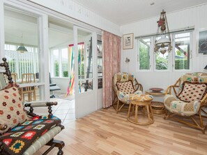 A room with a wooden floor, wicker furniture, a patterned sofa, and a view through a glass door. - 4 Person Holiday Home in Haderslev-by Traum (Haderslev)