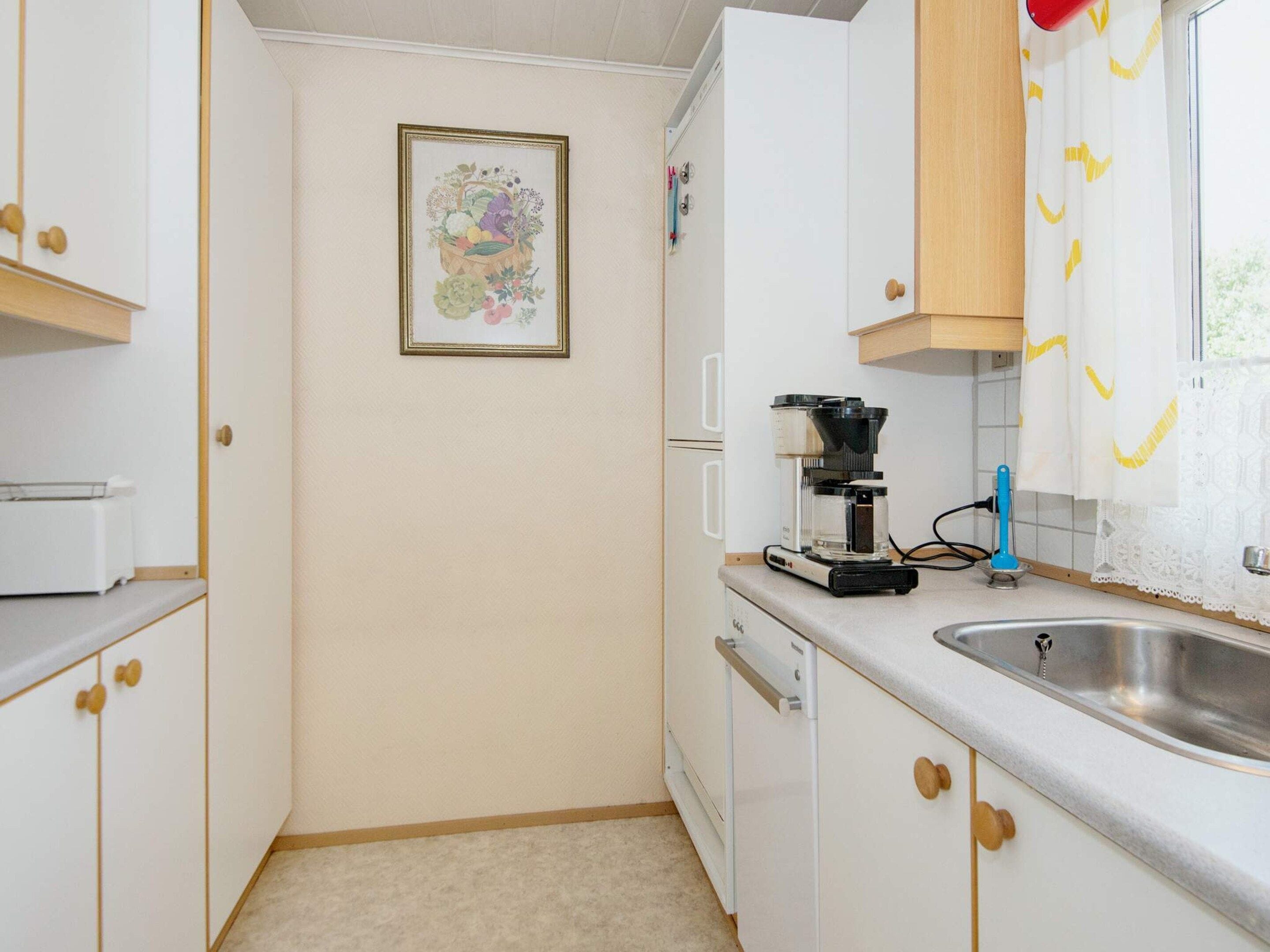 A compact kitchen with white cabinets, a coffee maker, and a sink.