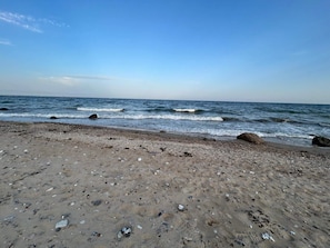 A beach with pebbles and rocks, a clear sky, and calm waves. - 4 Person Holiday Home in Haderslev-by Traum (Haderslev)