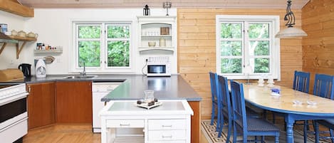 A modern kitchen with wooden cabinets, a central island, and a dining area with blue chairs.