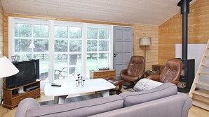 A cozy living room with a television, sofa, chairs, and a fireplace.