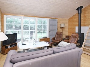 A cozy living room with a television, sofa, chairs, and a fireplace.