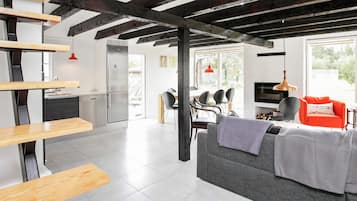 A modern interior with a kitchen, dining area, and living space featuring exposed beams, a sofa, and a TV.