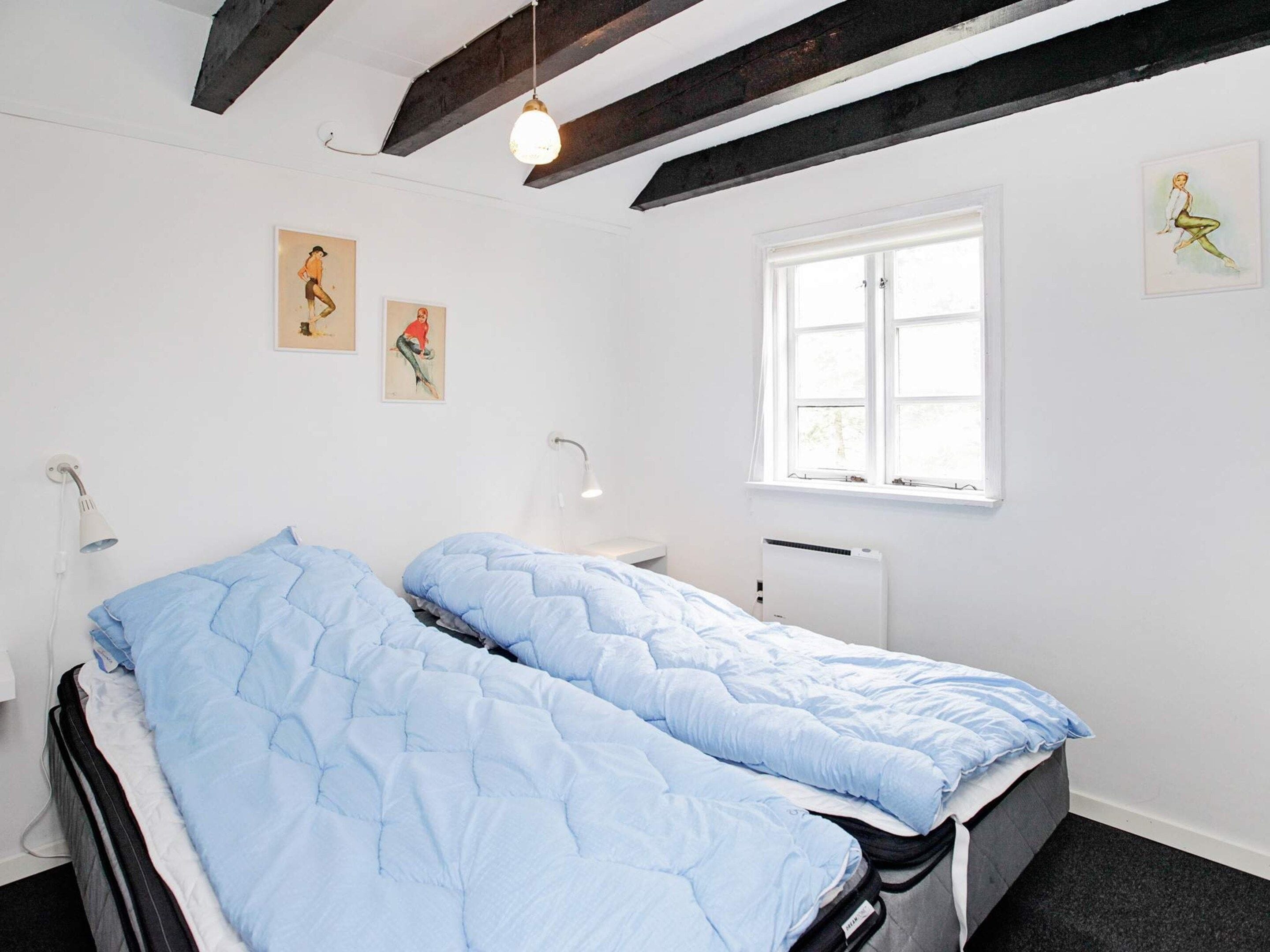 Un dormitorio con cama, ventana y obras de arte en las paredes.