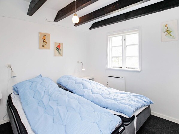 A bedroom with a bed, a window, and artwork on the walls.