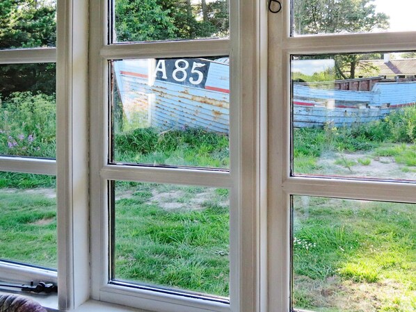 A window with a sign reading 'A85' and a view of a grassy area with a dilapidated structure in the background.