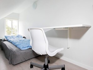 Et soveværelse med seng, skrivebord og stol samt et vindue.