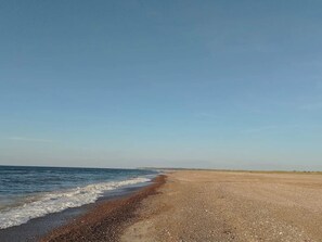 A beach with a pebbly shore and calm sea.