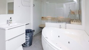 A modern bathroom with a white sink, a large bathtub, and a glass shower enclosure.